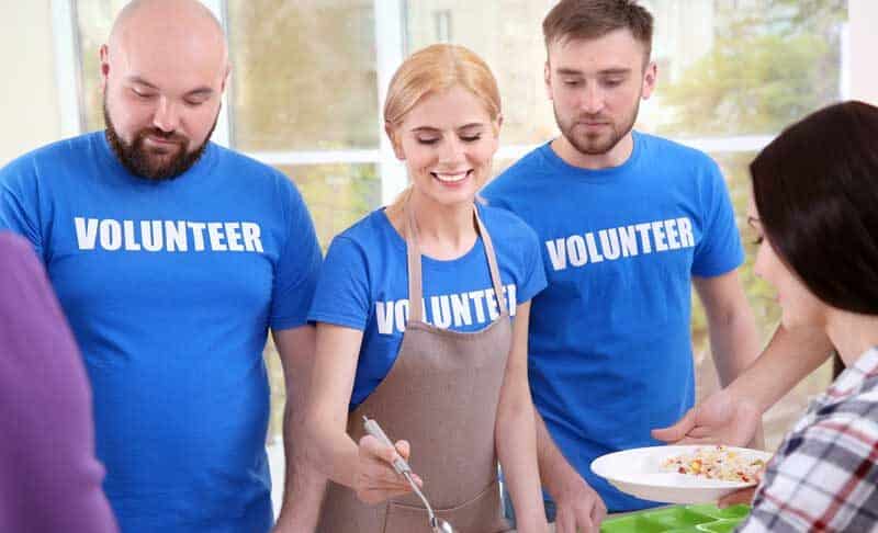 group of volunteers serving food at a charity for social media day