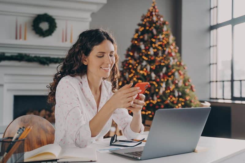 Woman at home on her phone receiving a holiday gift as a thank you from her company